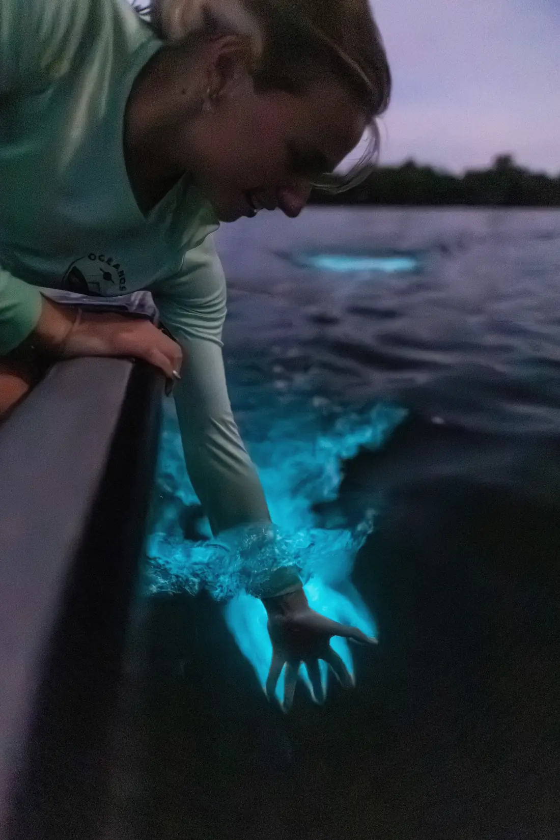 Hand holding bioluminescent water glowing blue at night on a La Parguera bioluminescent bay tour in Puerto Rico