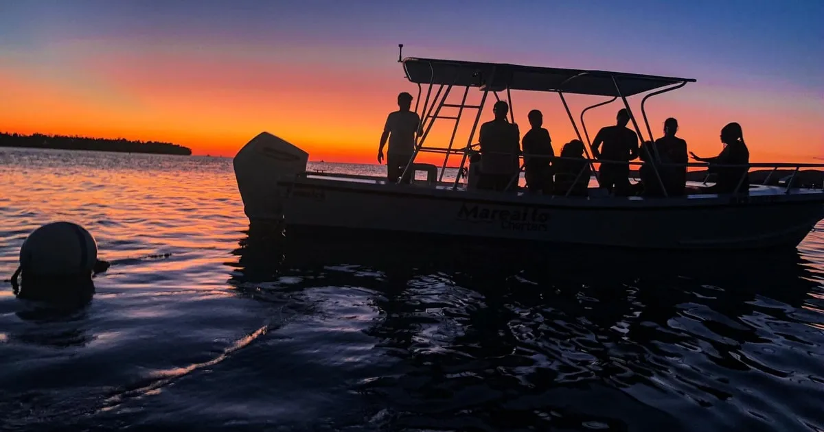 Sunset over the Caribbean with a tour boat anchored at Caracoles sandbar on a La Parguera bioluminescent bay cruise in Puerto Rico